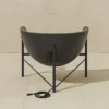 0001_GJ_KosmosChair2_Profile_.RGB_color.0020_1440x Modern black bowl chair on a metal stand placed on beige tiled floor; a coiled power cord lies in front.