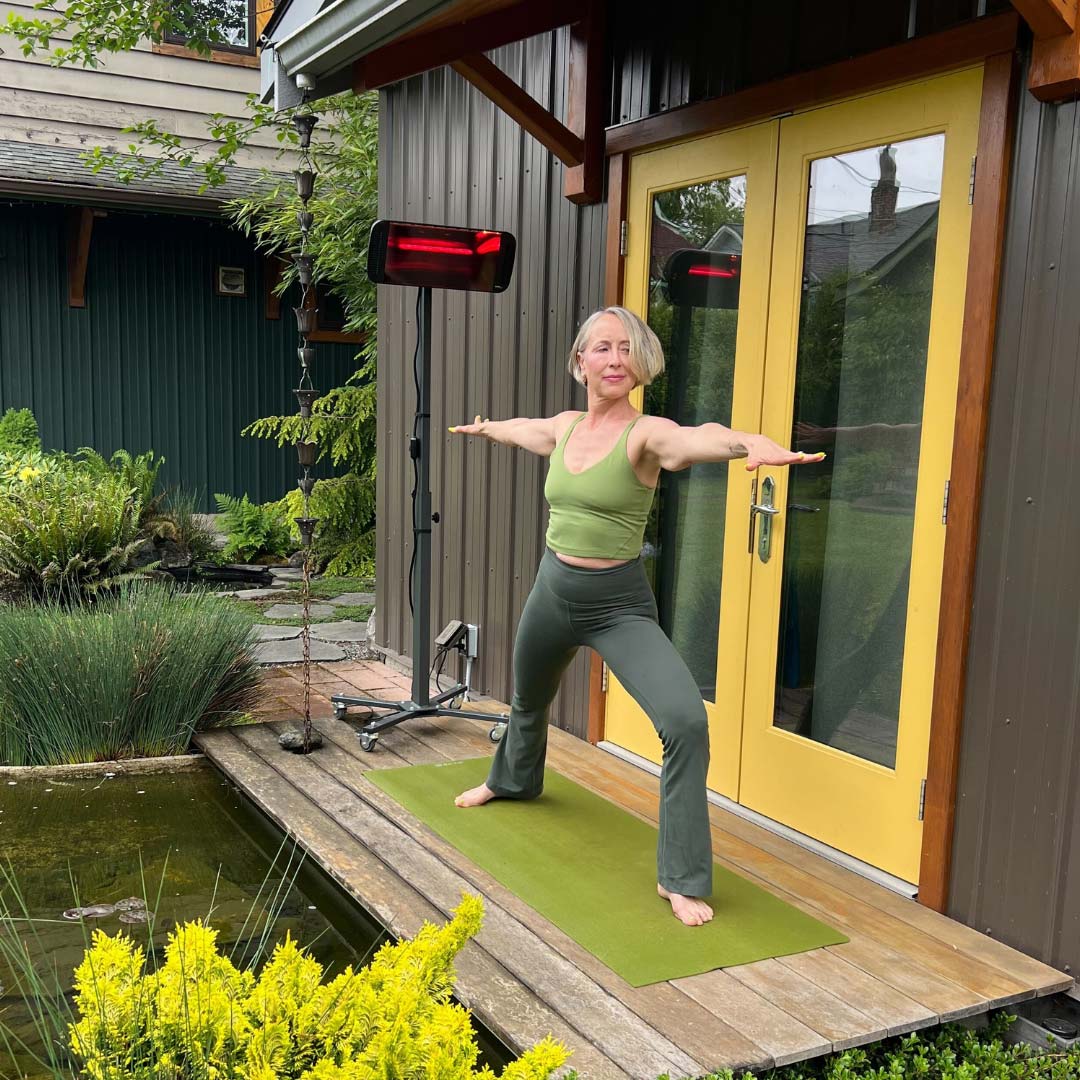 A woman in a yoga pose outside on a porch with the Heliosa 66 Black Heater behind her