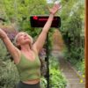 A woman in a yoga pose looking upward with a Heliosa 66 Black Heater behind her
