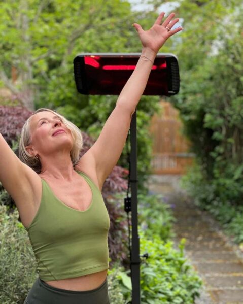 A woman in a yoga pose looking upward with a Heliosa 66 Black Heater behind her