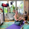 A woman sitting on a yoga mat indoors with a Heliosa 66 Black Heater behind her