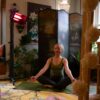 A woman sitting on a yoga mat indoors with a Heliosa 66 Black Heater behind her
